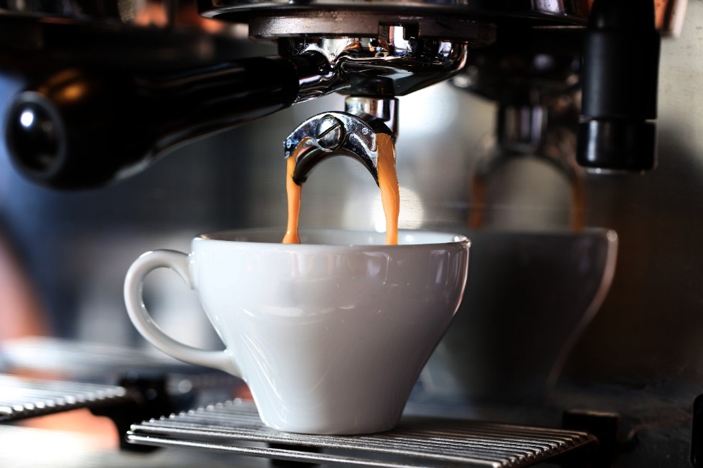 Espresso pouring from a cafe machine into a white cup
